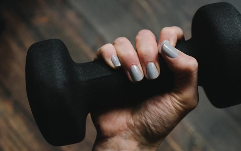 a person's hand with painted nails holding a dumbell